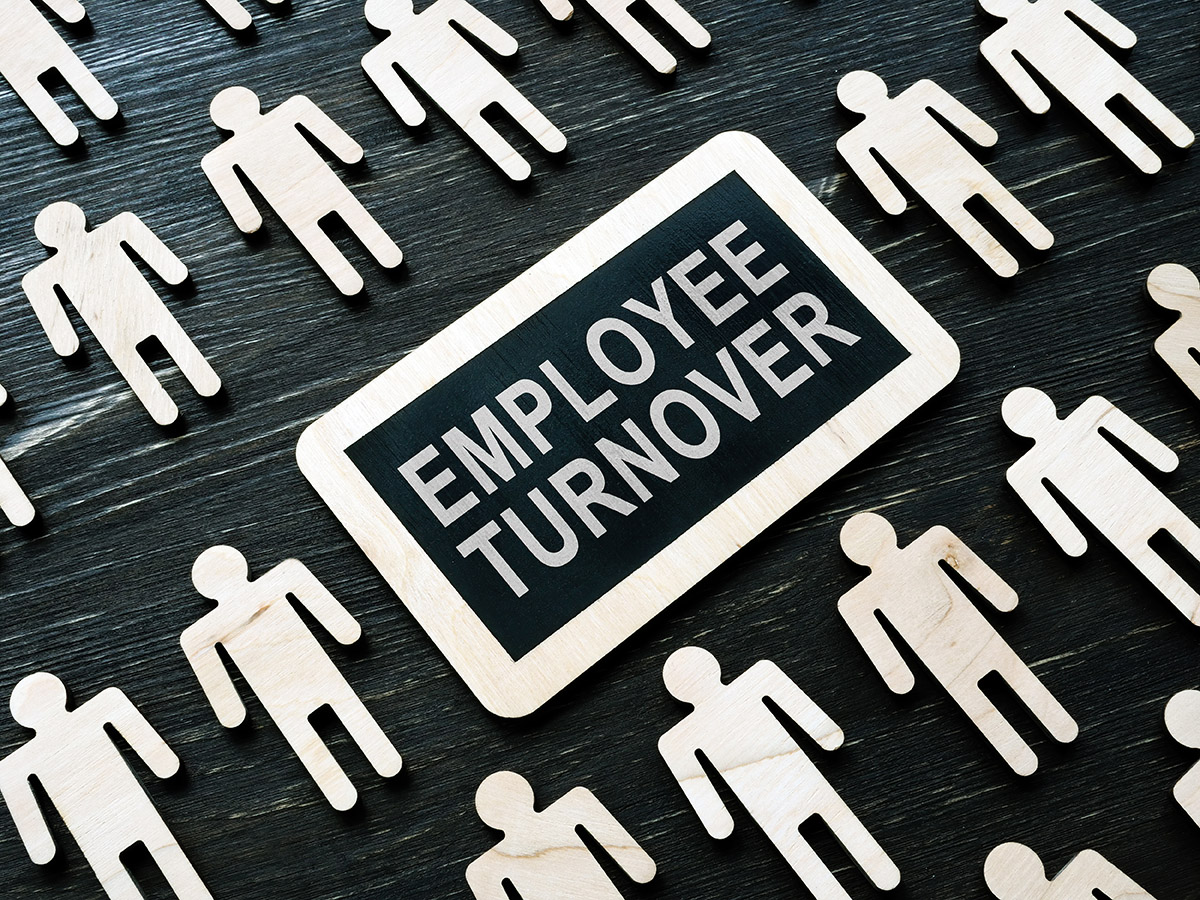 Image of figures surrounding a sign that says employee turnover.