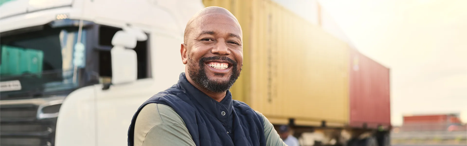 An image of a person smiling in front of a semi-truck