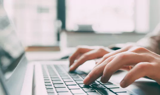 An image of two hands typing on a laptop